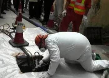 Reaching down to spray a sewer manhole 
